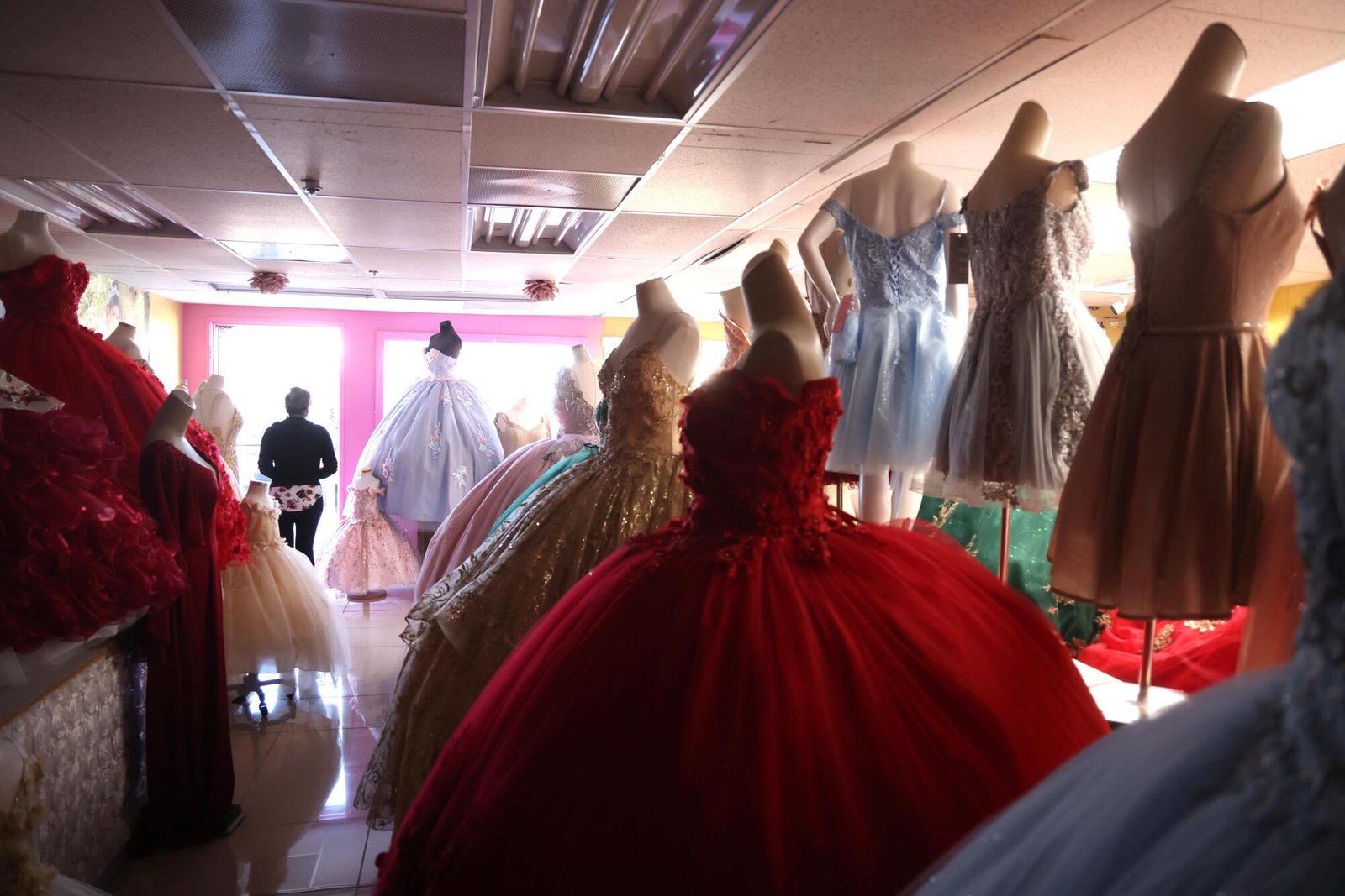 Donna in piedi davanti alla finestra vicino agli abiti quinceañera