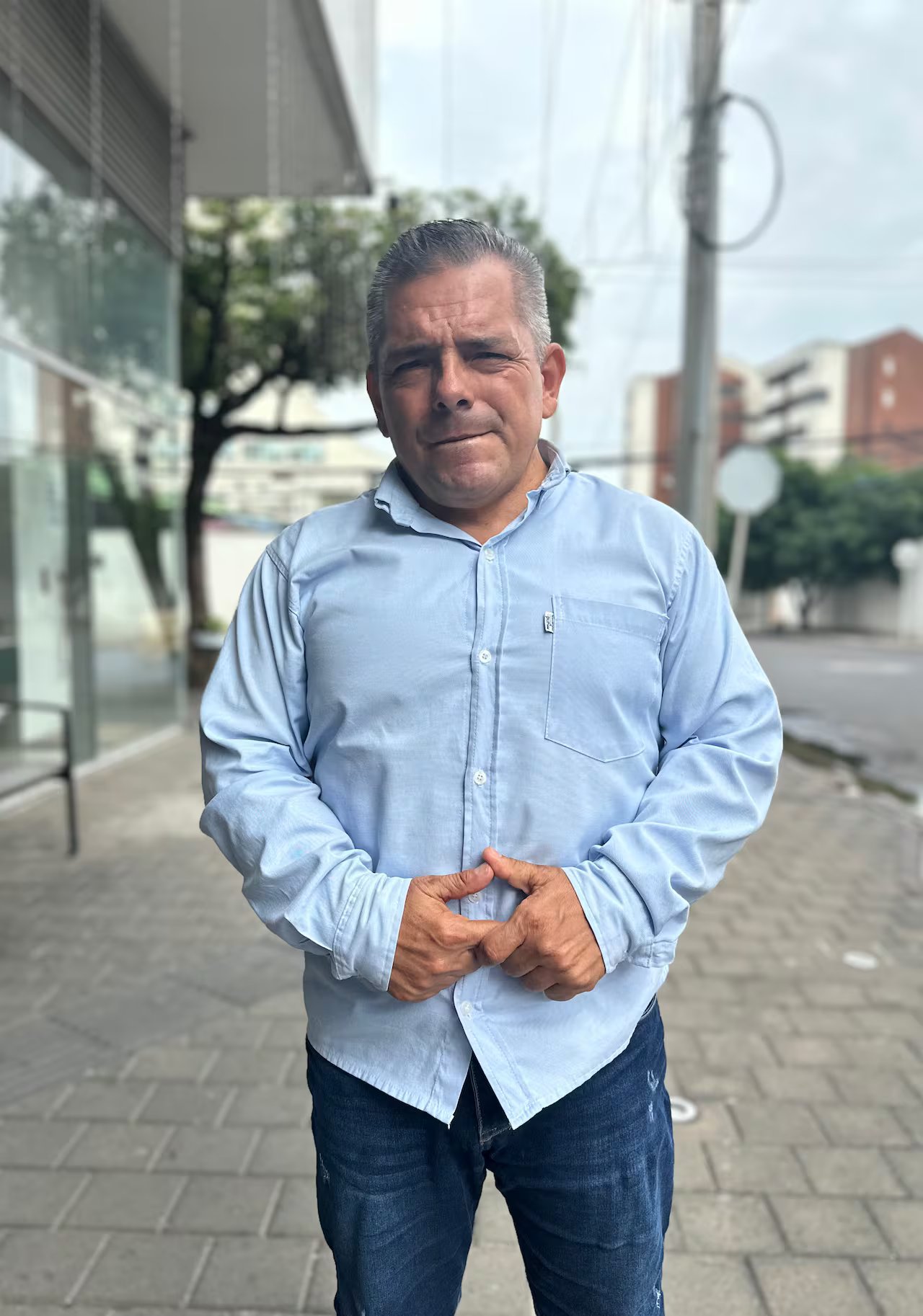 Un uomo sta sul marciapiede con le mani premute una davanti all'altra.