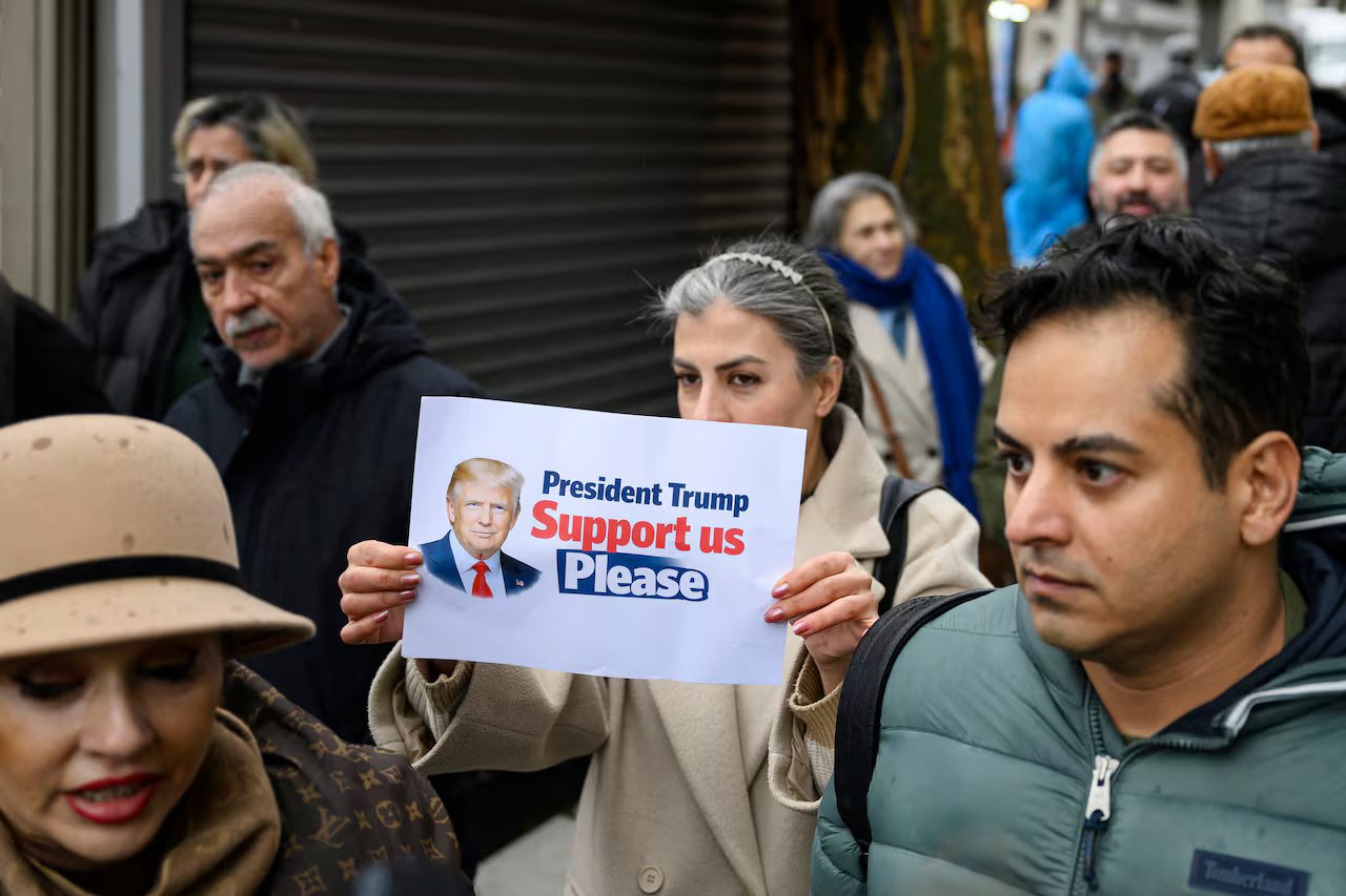 Un gruppo di manifestanti, uno dei quali tiene uno striscione con l'immagine del presidente americano Donald Trump