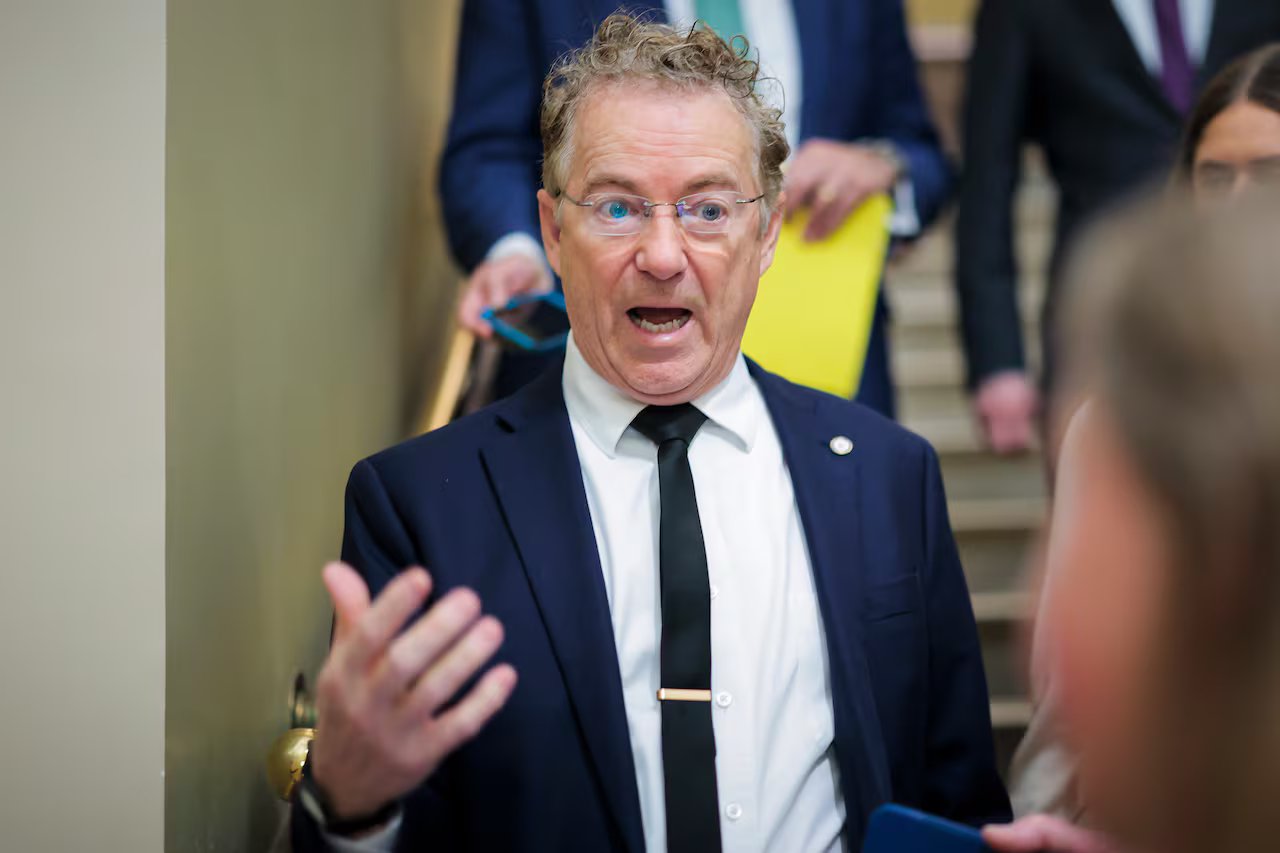 Un uomo con gli occhiali fa gesti durante una conversazione con i giornalisti