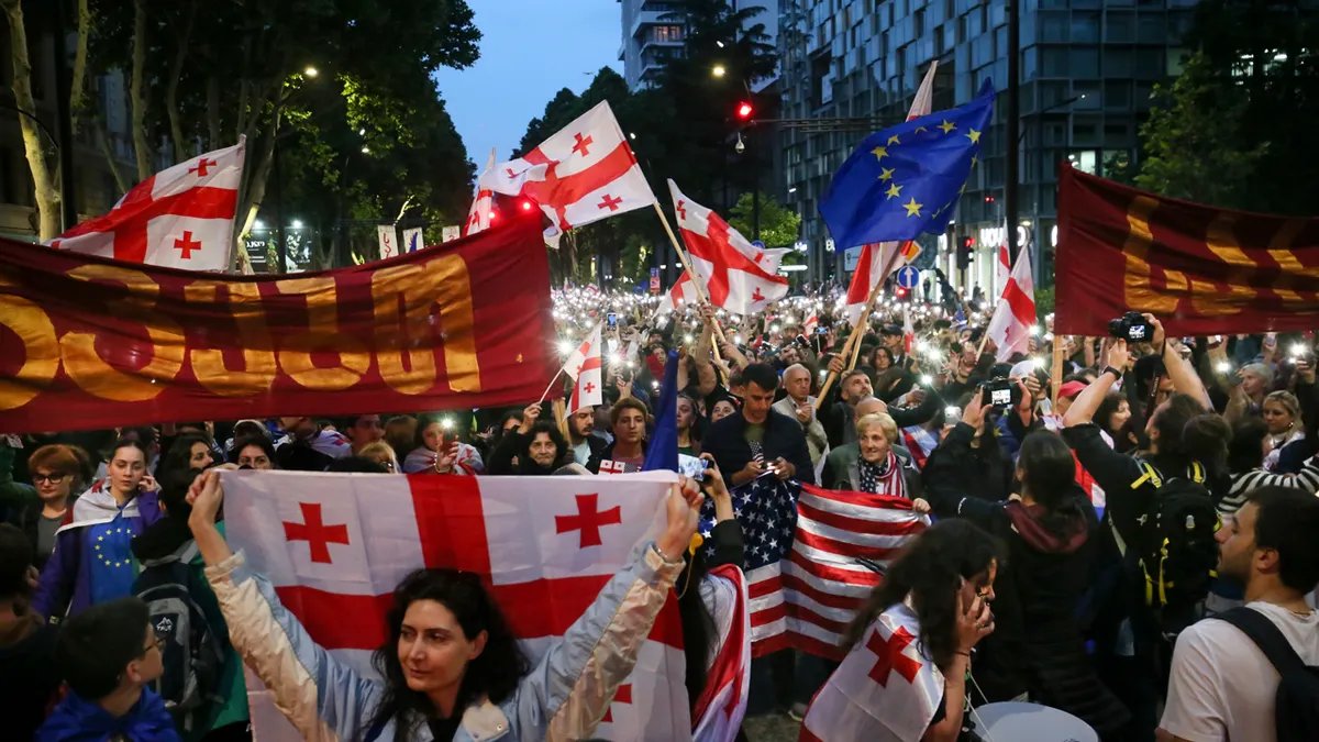 I manifestanti portano le bandiere nazionali della Georgia, degli Stati Uniti e dell'Unione europea durante una protesta dell'opposizione contro la legge sull'influenza straniera e la celebrazione del Giorno dell'Indipendenza.