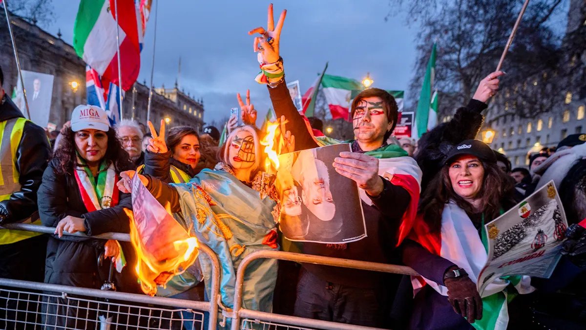I manifestanti hanno dato fuoco a foto stampate durante una manifestazione in una strada nel centro di Londra, con bandiere e striscioni iraniani visibili nelle vicinanze.