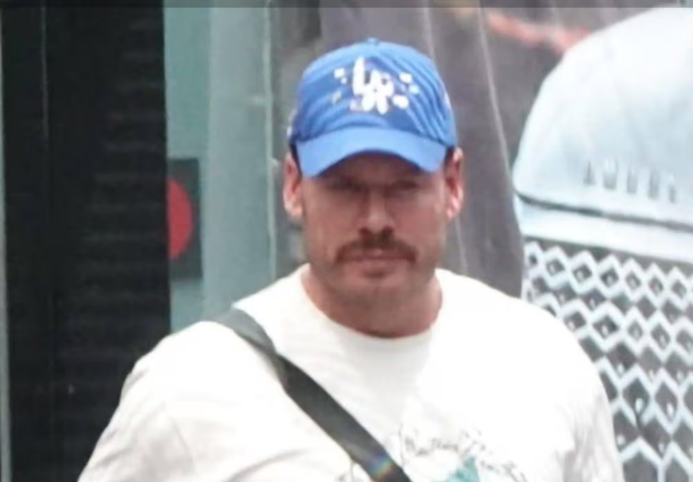 Uomo che indossa un berretto da baseball, una maglietta e jeans, le mani in tasca