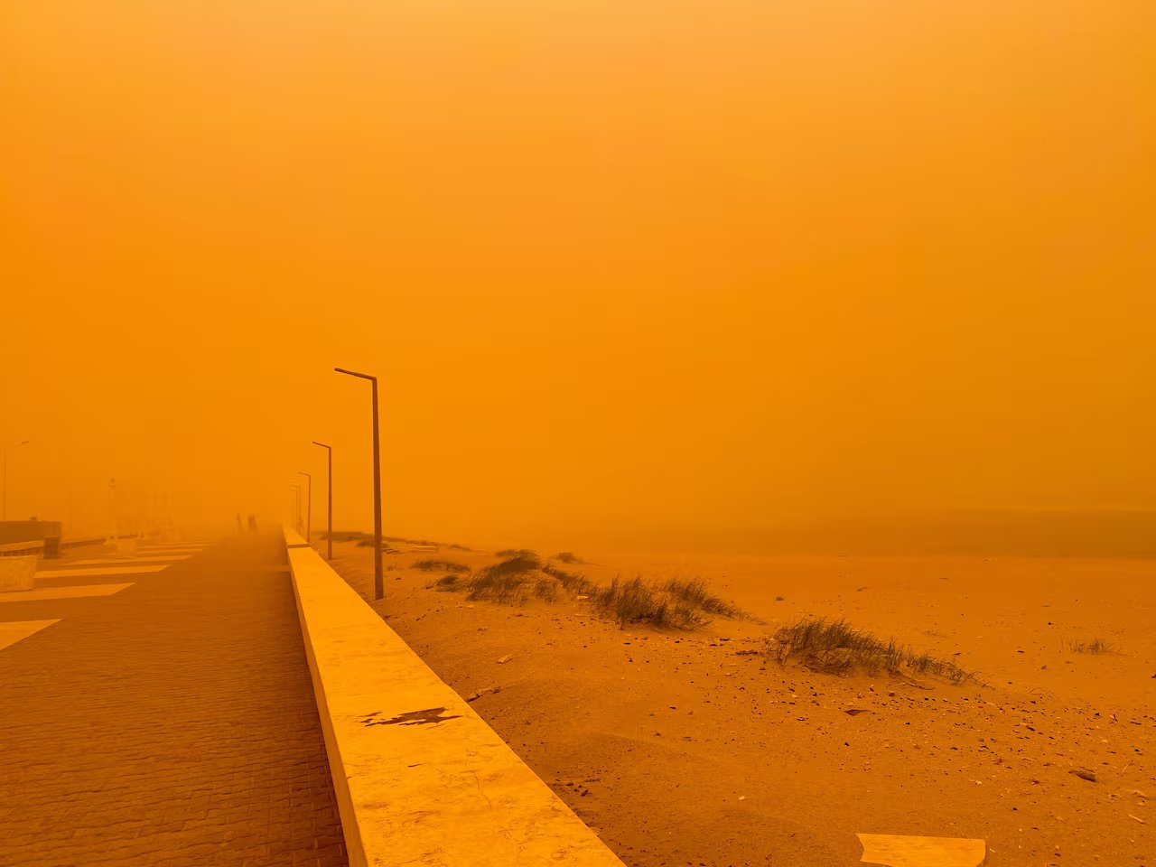 Scena arancione di una strada vuota lungo la costa a causa di una tempesta di polvere.