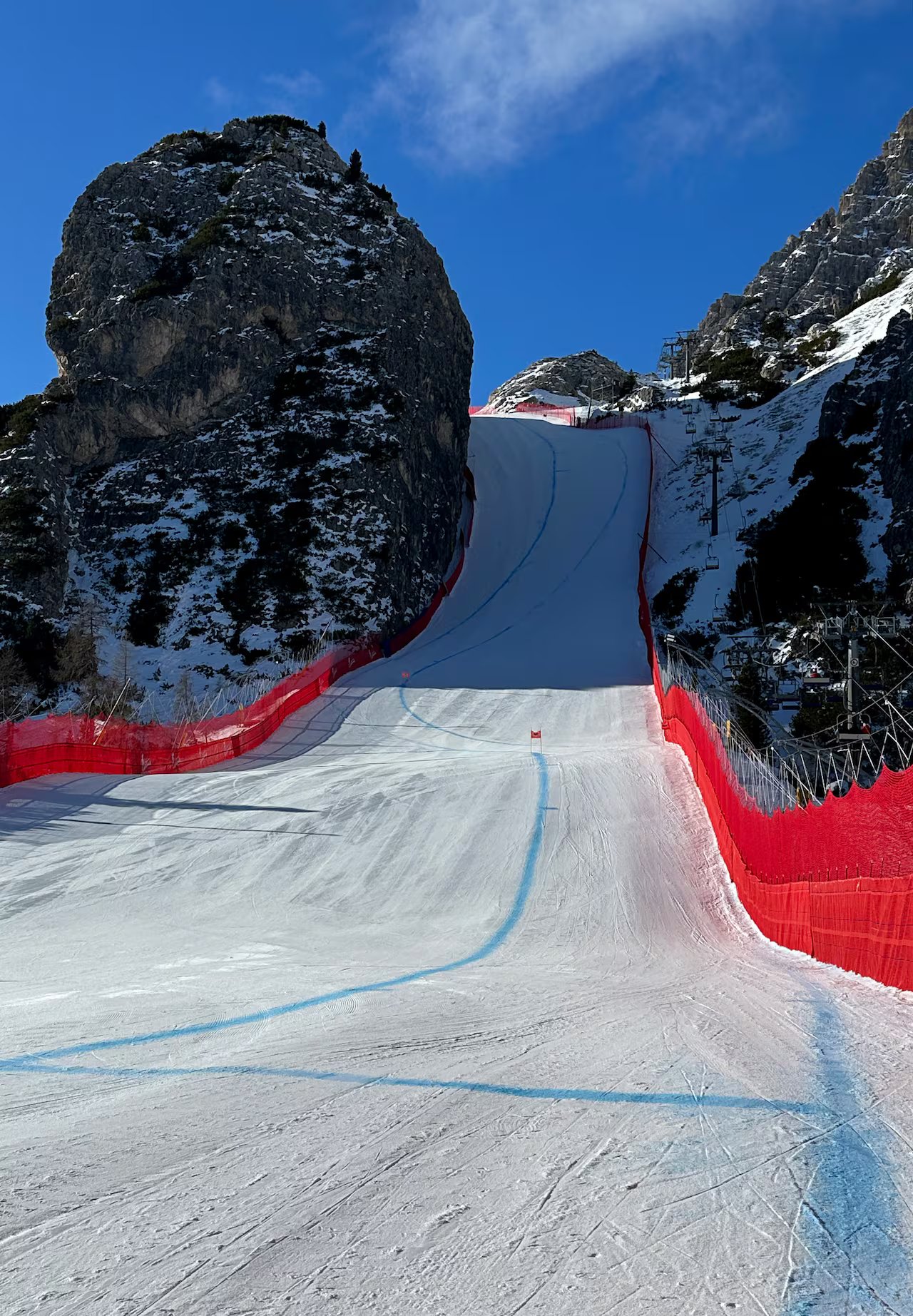 La pista da sci da discesa si trova tra due gigantesche pareti rocciose ed è delimitata da guardrail di colore arancione brillante. 