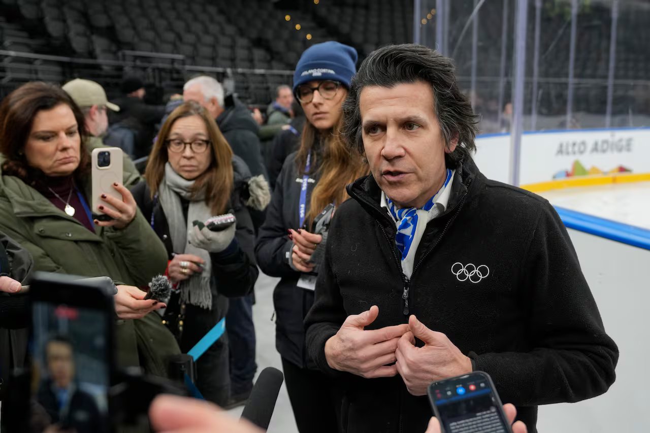 Un uomo parla con i giornalisti in un'arena di hockey.