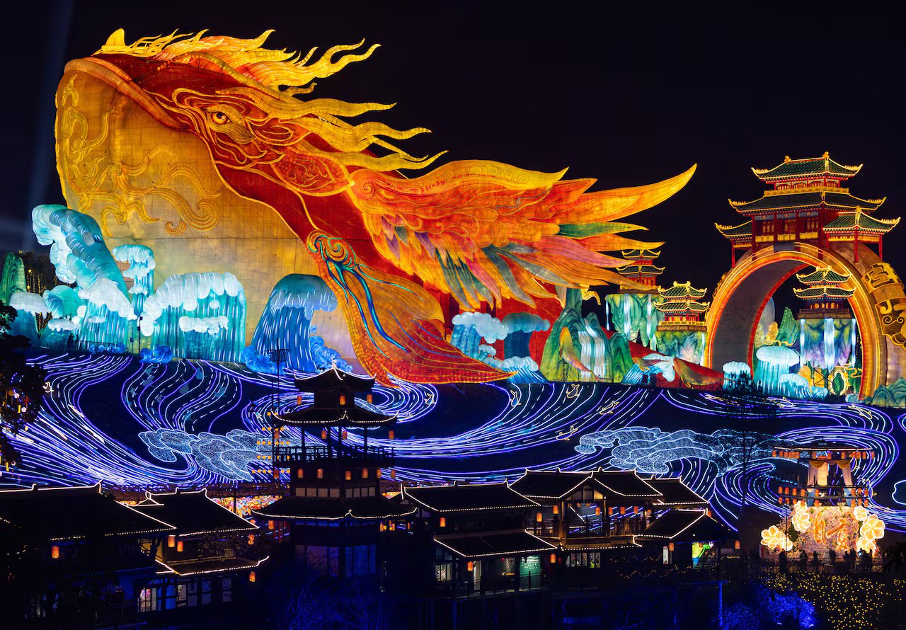 Una lanterna gigante a forma di pesce rosso ha delle onde sotto di essa e di notte le strutture del tempio sono illuminate da luci esterne.