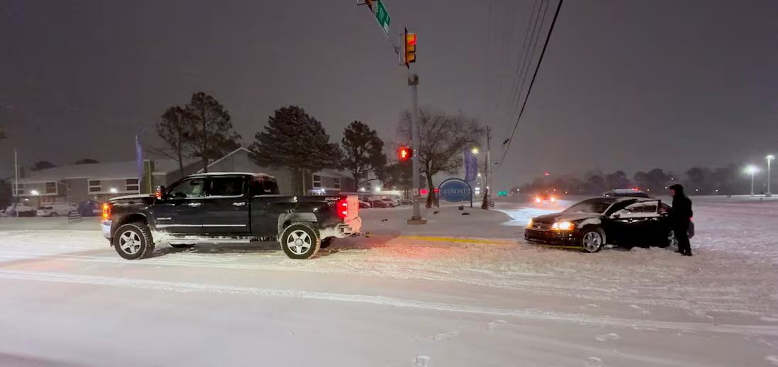 Un camioncino rimorchia un'auto bloccata nella neve all'alba.