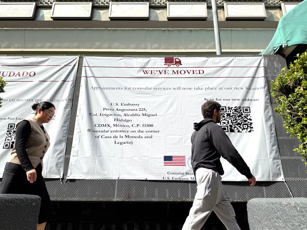 La gente passa davanti a un grande cartello sul lato di un edificio che informa che l'ambasciata americana a Città del Messico si è trasferita.
