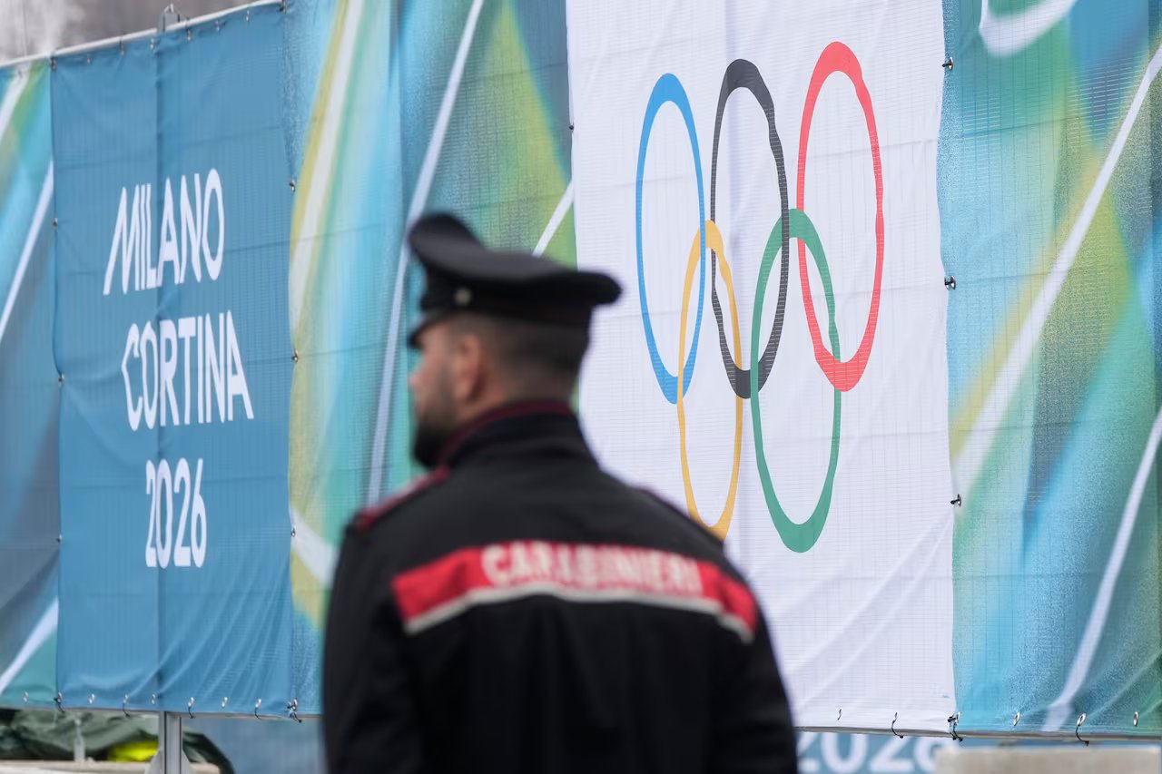 Un agente di polizia è visto di spalle, camminare davanti a uno striscione con sopra gli anelli olimpici