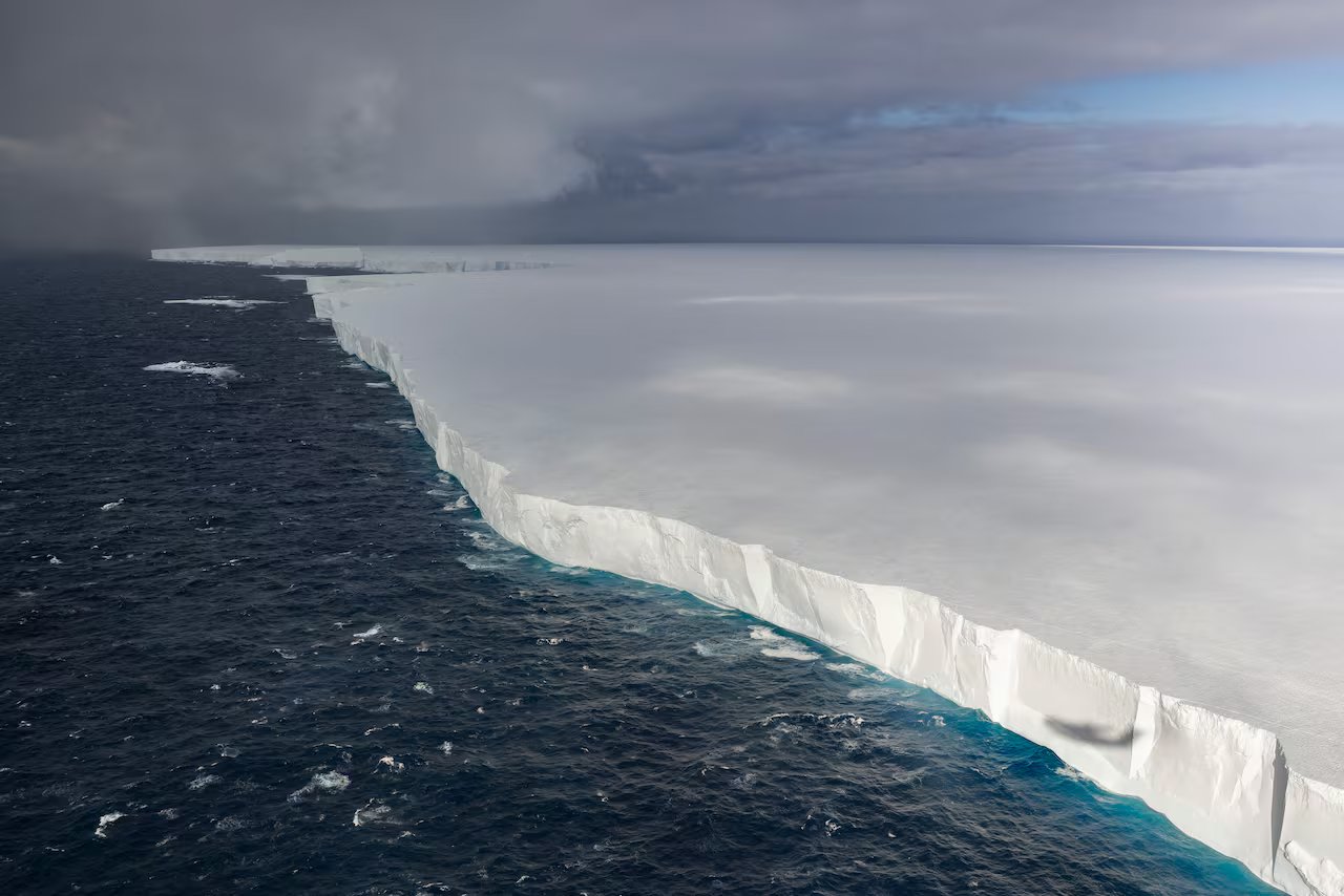 Vista aerea di un grande iceberg bianco piatto sull'acqua blu scuro. 