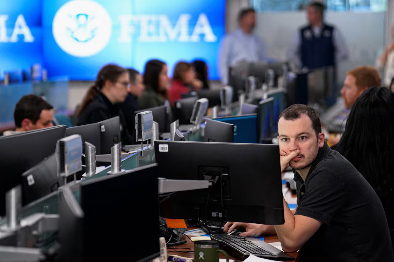 Le persone lavorano in un ufficio aperto e fissano gli schermi dei computer.