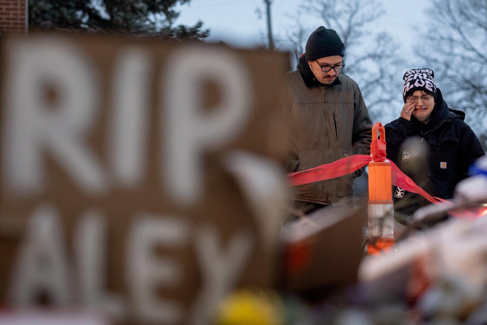 Una persona si asciuga le lacrime mentre visita un memoriale per Alex Pretty