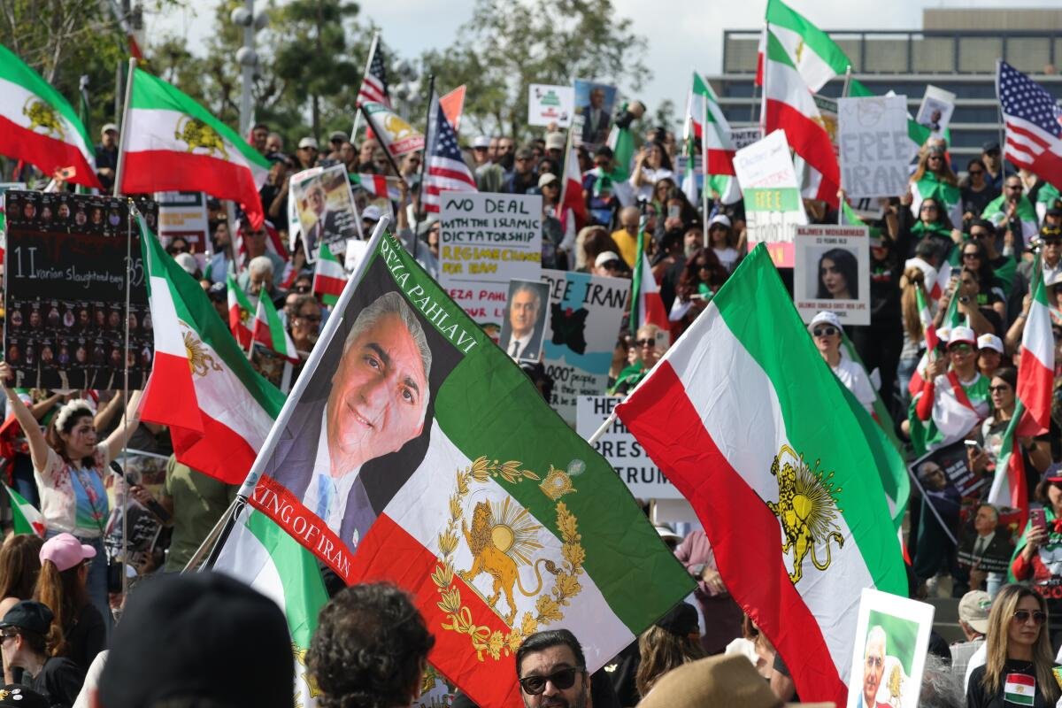 Persone che portano bandiere non ufficiali del leone e del sole iraniani e striscioni di protesta marciano