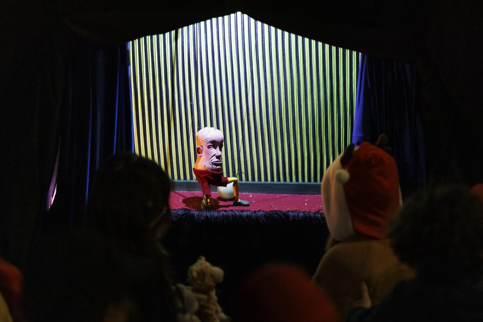 Una bambola con un'enorme testa a uovo su un corpo con pantaloni rossi.