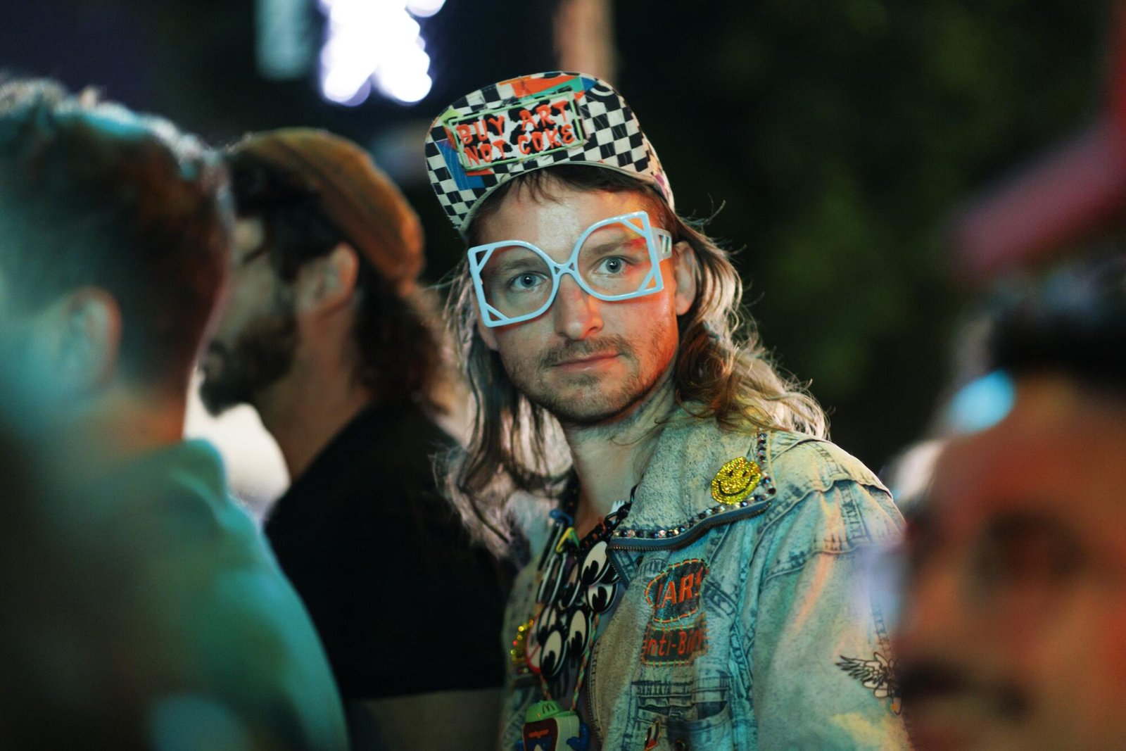 Uomo che indossa occhiali, cappello quadrato e giacca di jeans lavata con campioni.