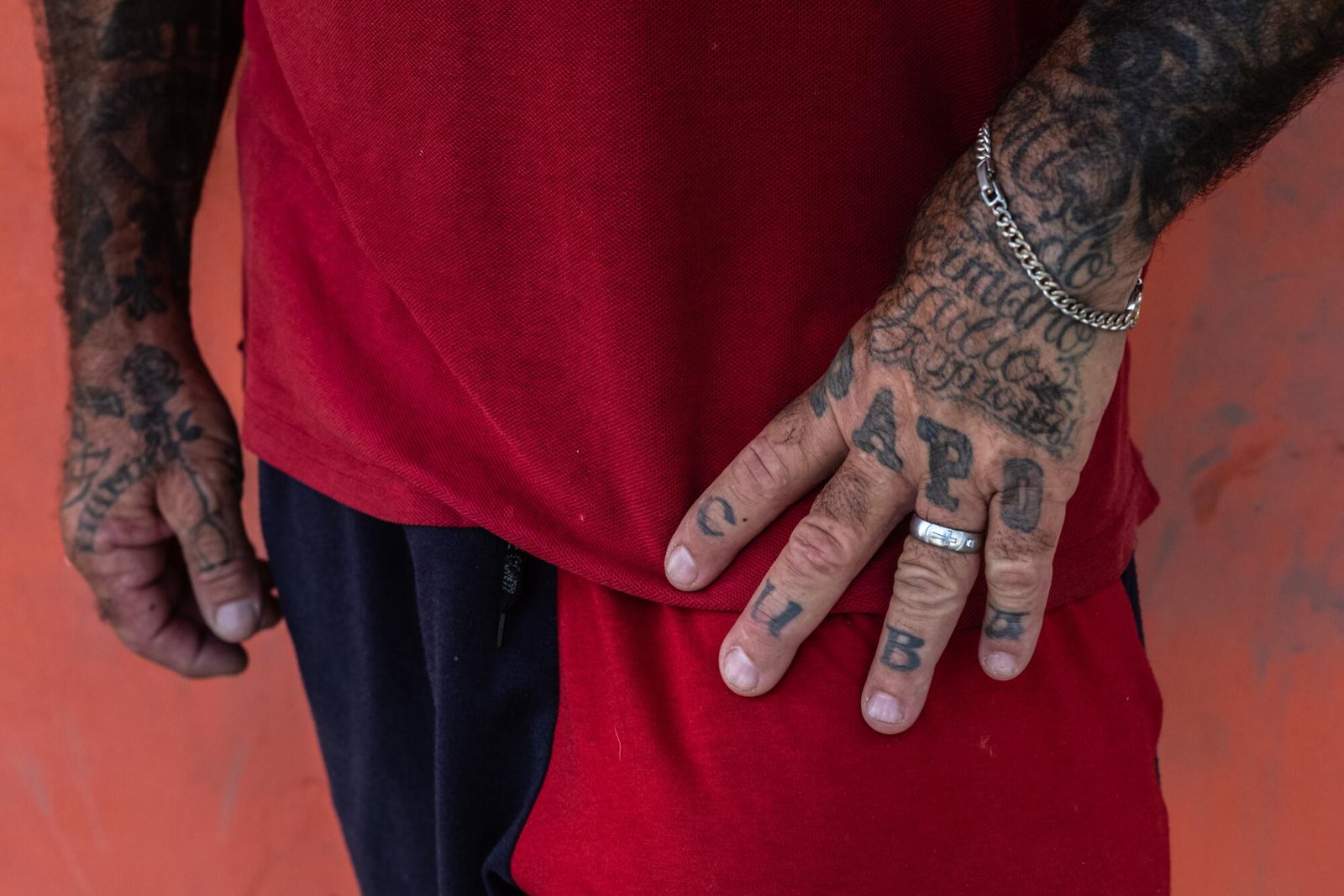Incisione di una persona che indossa una maglietta rossa che mostra le sue mani tatuate